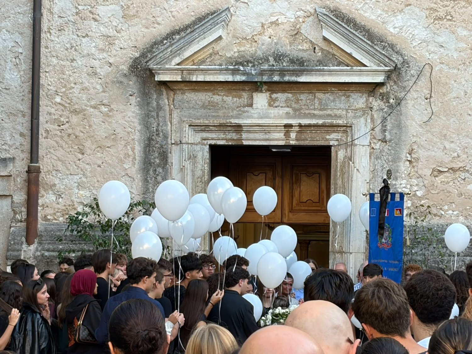 https://www.tp24.it/immagini_articoli/21-10-2026/1792598352-0-trapani-l-ultimo-saluto-ad-alessandro-savona-gli-amici-abbracciati-attorno-alla-bara-poi-i-palloncini-bianchi.jpg